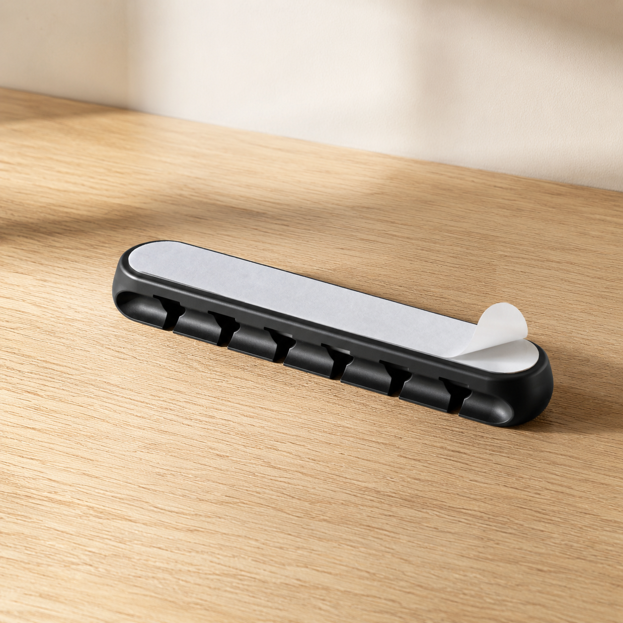 Adhesive backing on a black five-slot cable holder