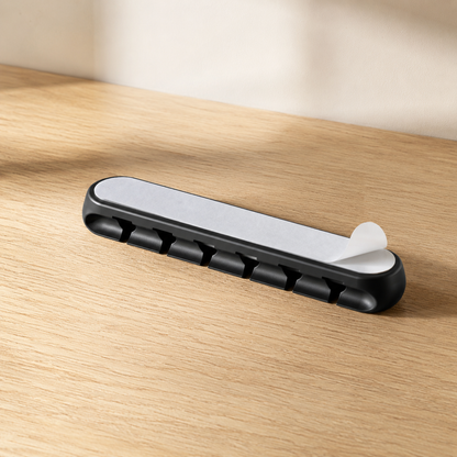 Adhesive backing on a black five-slot cable holder